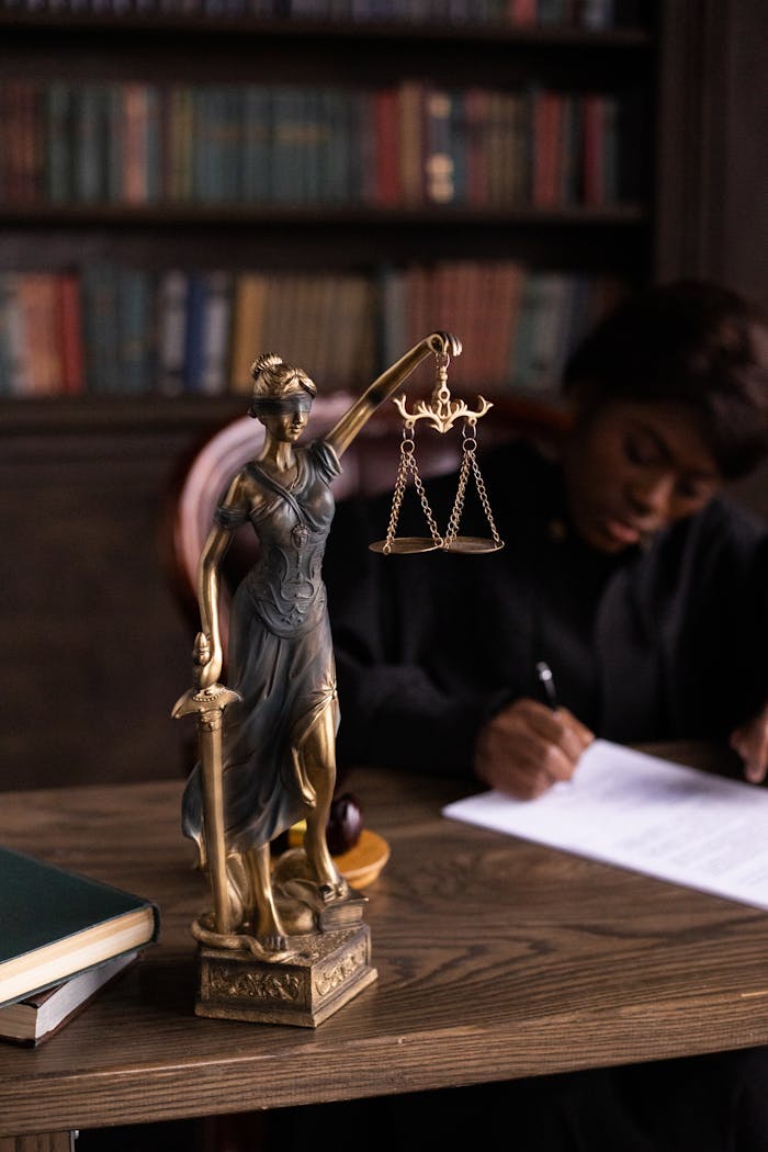 our-journey-02 Close-up of Lady Justice figurine on a lawyer's desk with books and documents.