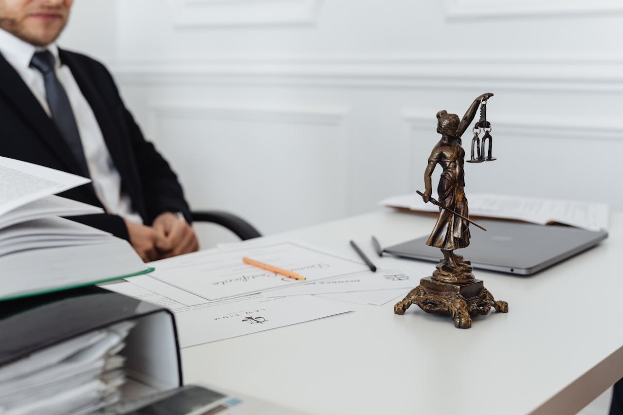 why-choose-us A legal professional's workspace featuring Lady Justice statue, documents, and a laptop.