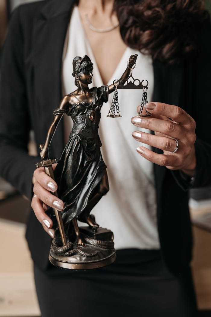 who-we-are Close-up of Lady Justice statuette held by a lawyer, symbolizing law and justice.