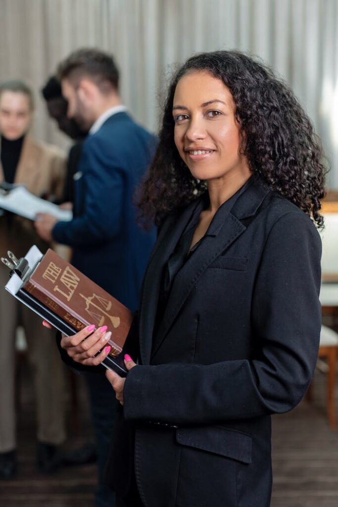 African American female lawyer holding a law book in an office setting, showcasing professionalism and legal expertise.